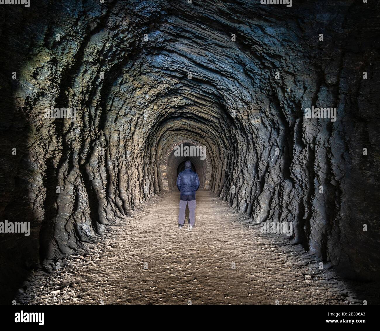 Person, die in einen alten Eisenbahntunnel geht, Otago, Neuseeland. Stockfoto