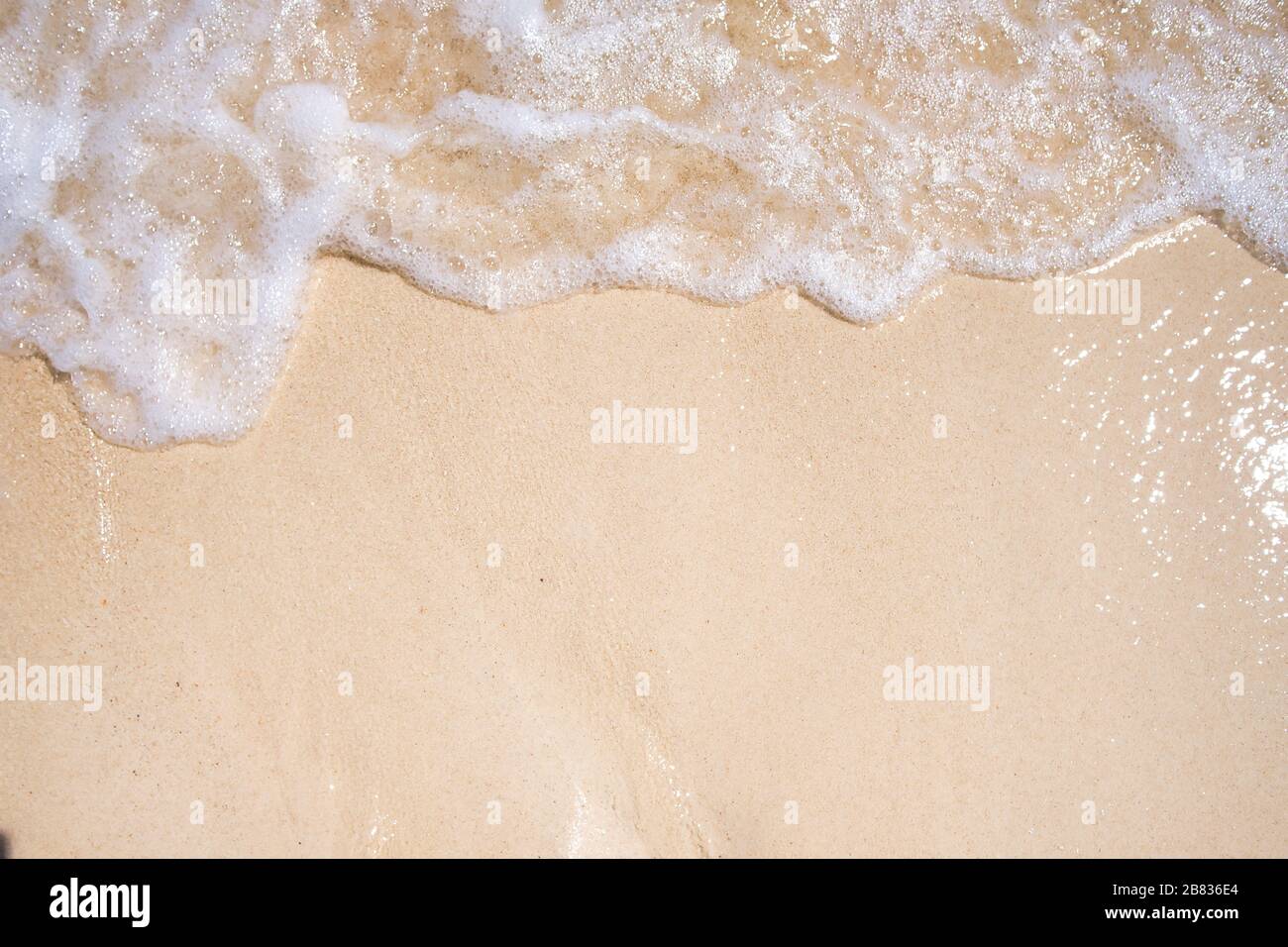 Sanftes blaues Meer am sauberen Sandstrand. Die blaue Meeresweiche Welle auf dem Sand berührt kontinuierlich und schön das Ufer Stockfoto