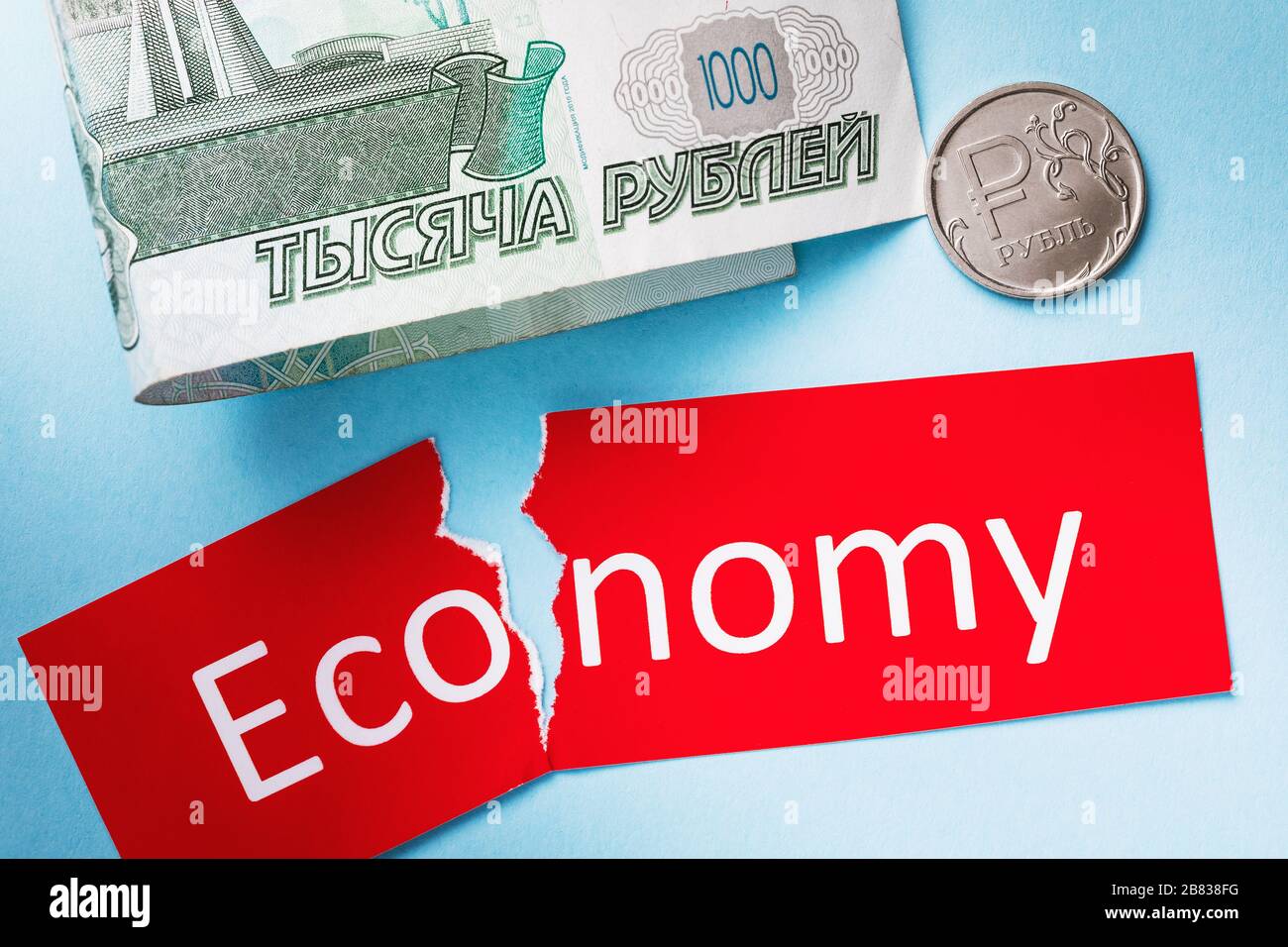 Russisches Geld und ein zerrissener Tag mit Text. Konzept zum Thema des wirtschaftlichen Rückgangs im Land und der Abschreibung der Währung Stockfoto