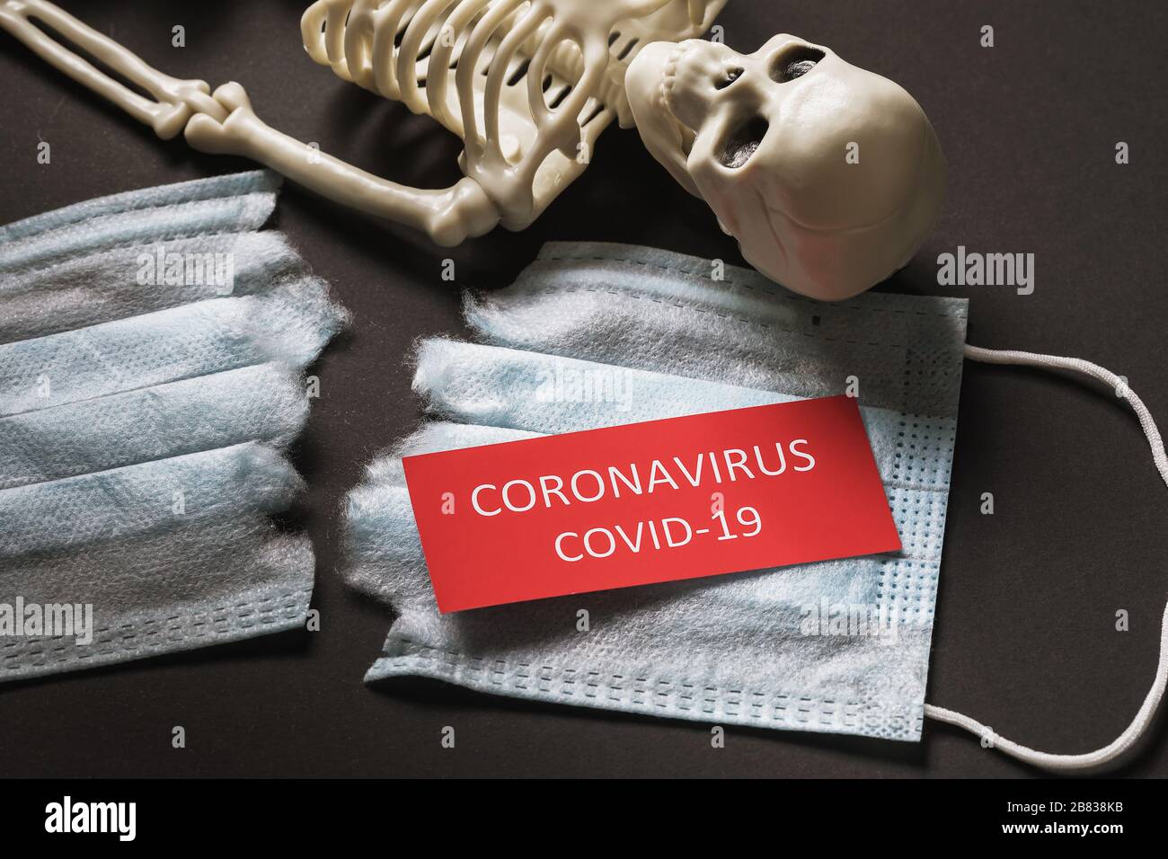 Menschliches Skelett, zerrissene medizinische Maske und Tag mit Text. Das Konzept der Opfer von Coronavirus COVID-19 Stockfoto