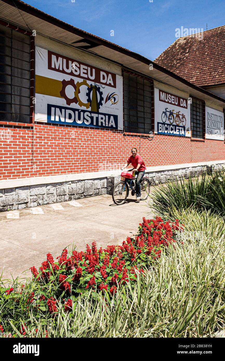 Frau, die auf dem Bürgersteig ein Fahrrad fährt. Joinville, Santa Catarina, Brasilien. Stockfoto