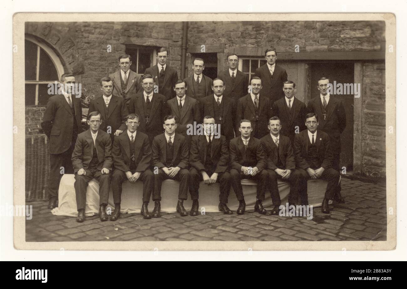 Originalpostkarte aus dem frühen 20. Jahrhundert mit einer Gruppe von Mitarbeitern in der Mühle, die elegante Anzüge tragen, posieren für ein Gruppenfoto draußen, Perseverance Mill, (Albion Mill) Padiham, Burnley, Lancashire, England, Großbritannien 1919 Stockfoto