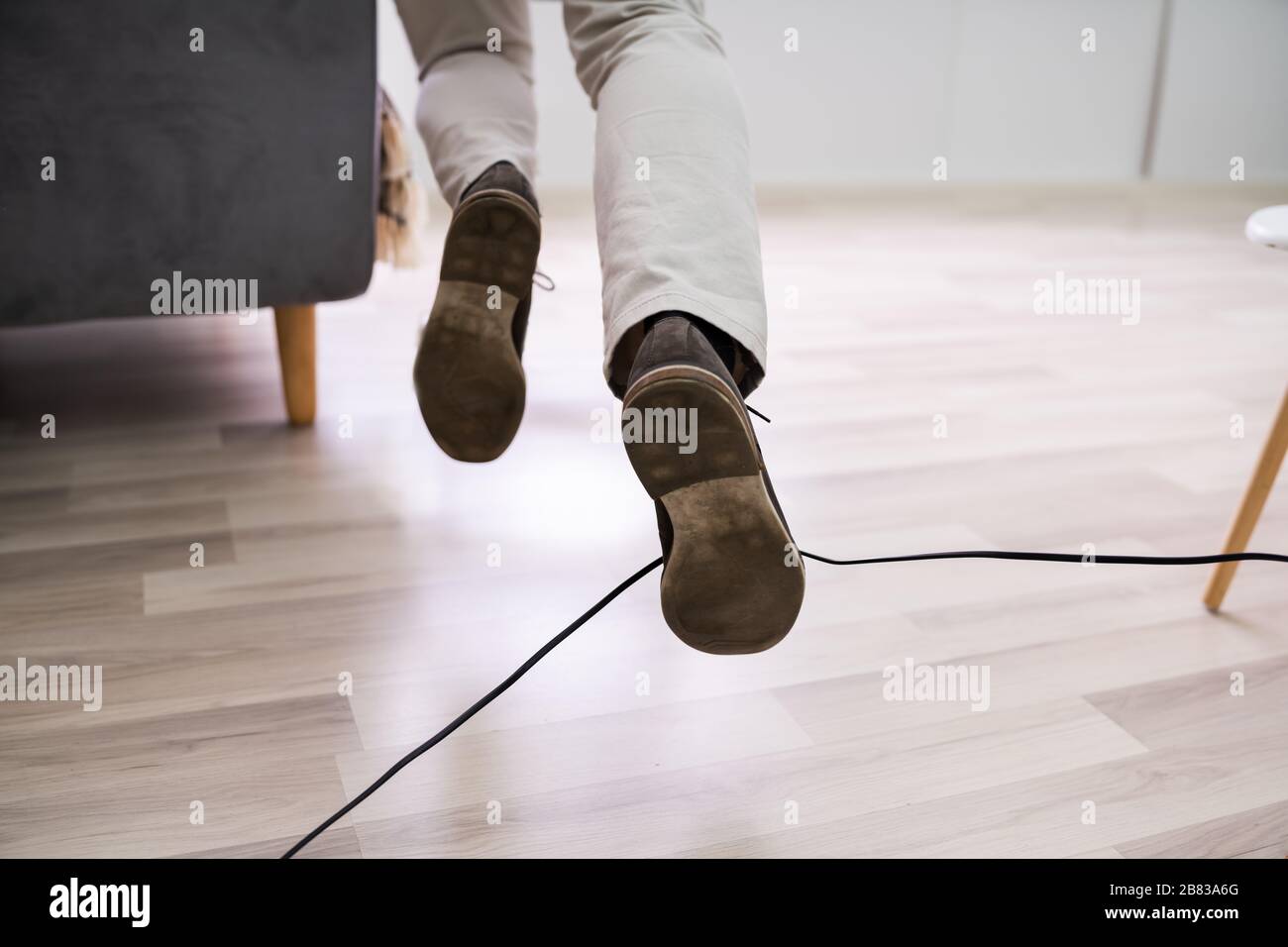 Nahaufnahme EINES Mannes, der mit einem Elektrokabel zu Hause stolpert Stockfoto