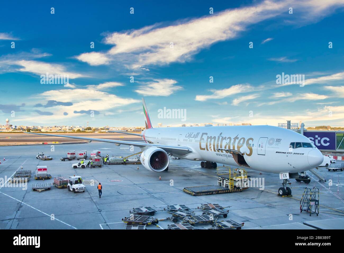 Eine Emirates Boeing 777 - 300er, das größte Passagierflugzeug der Welt, wartet bei Sonnenuntergang auf Passagiere und Verladung am Flughafen Bahrein. Stockfoto