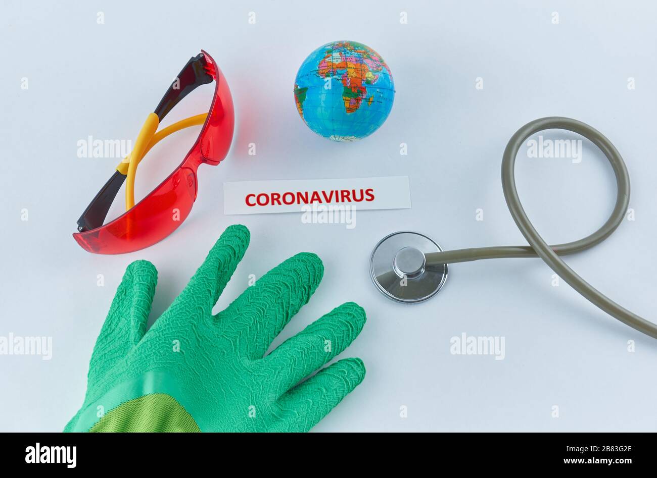 Coronavirus-Etikett neben Schutzkleidung, Stethoskop und Weltkugel Stockfoto