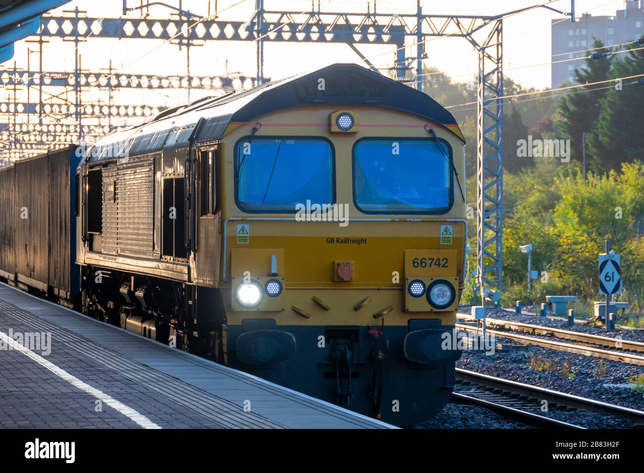 Elektrolokomotive der Klasse 66, die einen Güterzug durch Rugby Station, Warwickshire, England transportiert Stockfoto