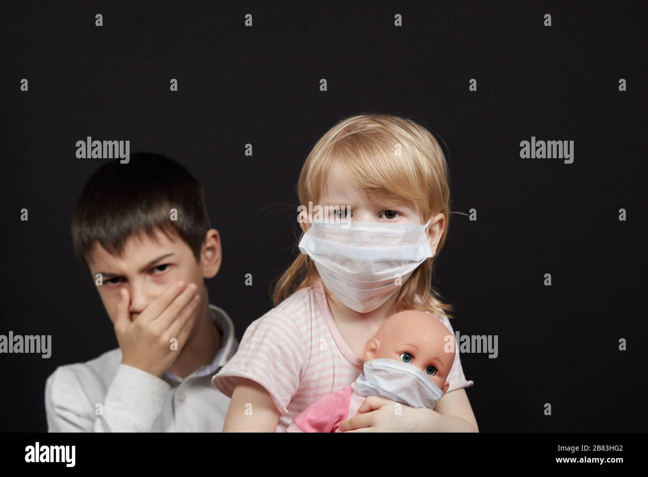 Maskiertes Mädchen und Junge niesen, das Konzept des Schutzes vor der Verbreitung der virusmedizinischen Maske. Stockfoto