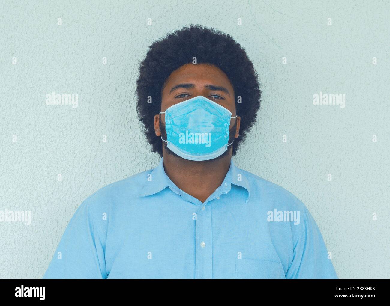 Ein Mann in einem blauen Hemd mit einer medizinischen Maske, um Ansteckungen zu vermeiden Stockfoto