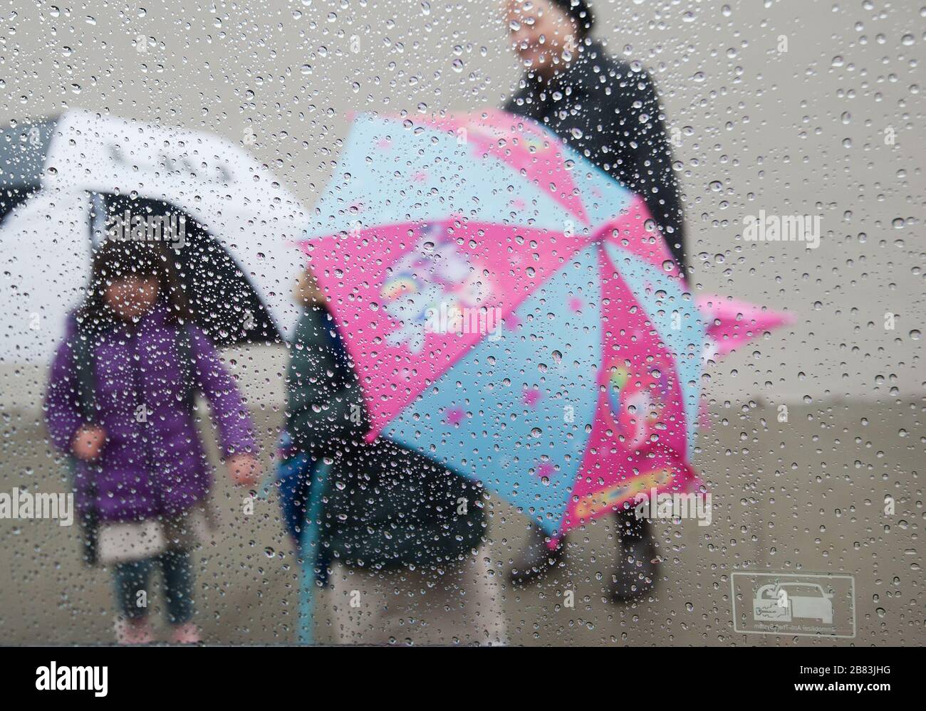 Erwachsene mit zwei Kindern und Regenschirmen Stockfoto