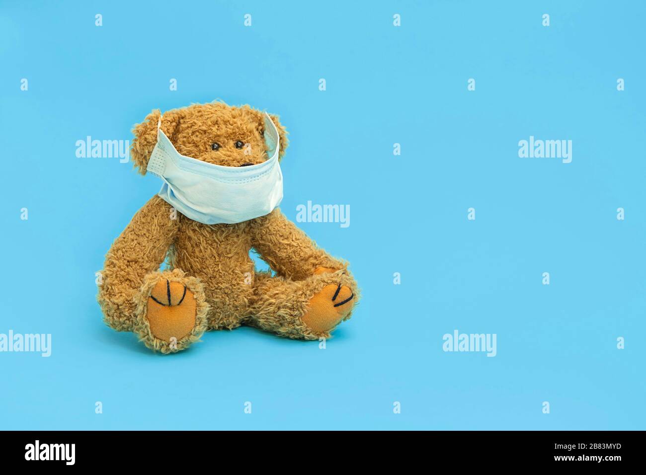 Schutz vor Virus-Konzept. Teddybär trägt eine medizinische Maske auf blauem Hintergrund mit Kopierraum. Stockfoto