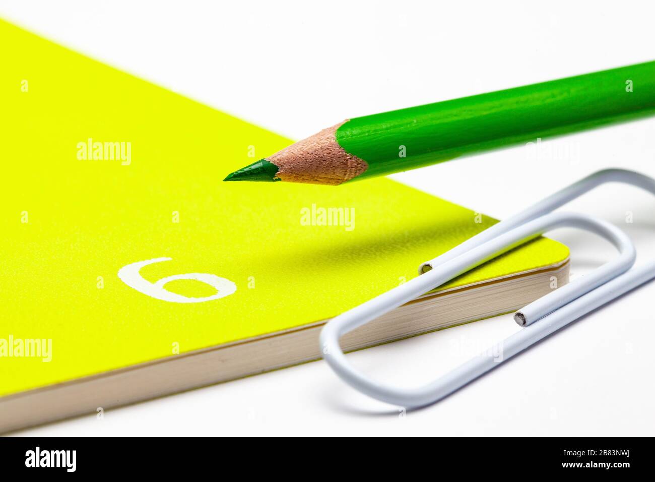 Organisator für den Monat Juni, grüner Bleistift und weiße Büroklammer auf dem weißen Tisch. Stockfoto