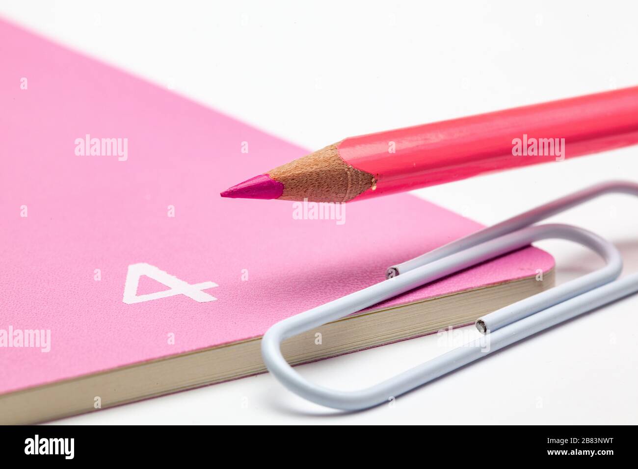 Organisator für den Monat April, pinkfarbener Bleistift und weiße Büroklammer auf dem weißen Tisch. Stockfoto
