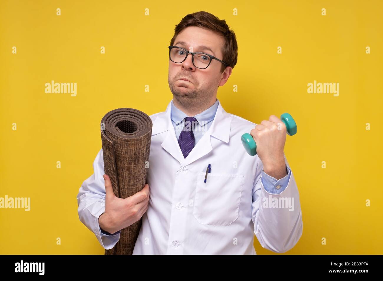 Ein reifer kaukasischer Mannarzt, der Hanteln hält und Ratschläge zu einem gesunden Lebensstil gibt. Sport- und Medizinkonzept. Stockfoto