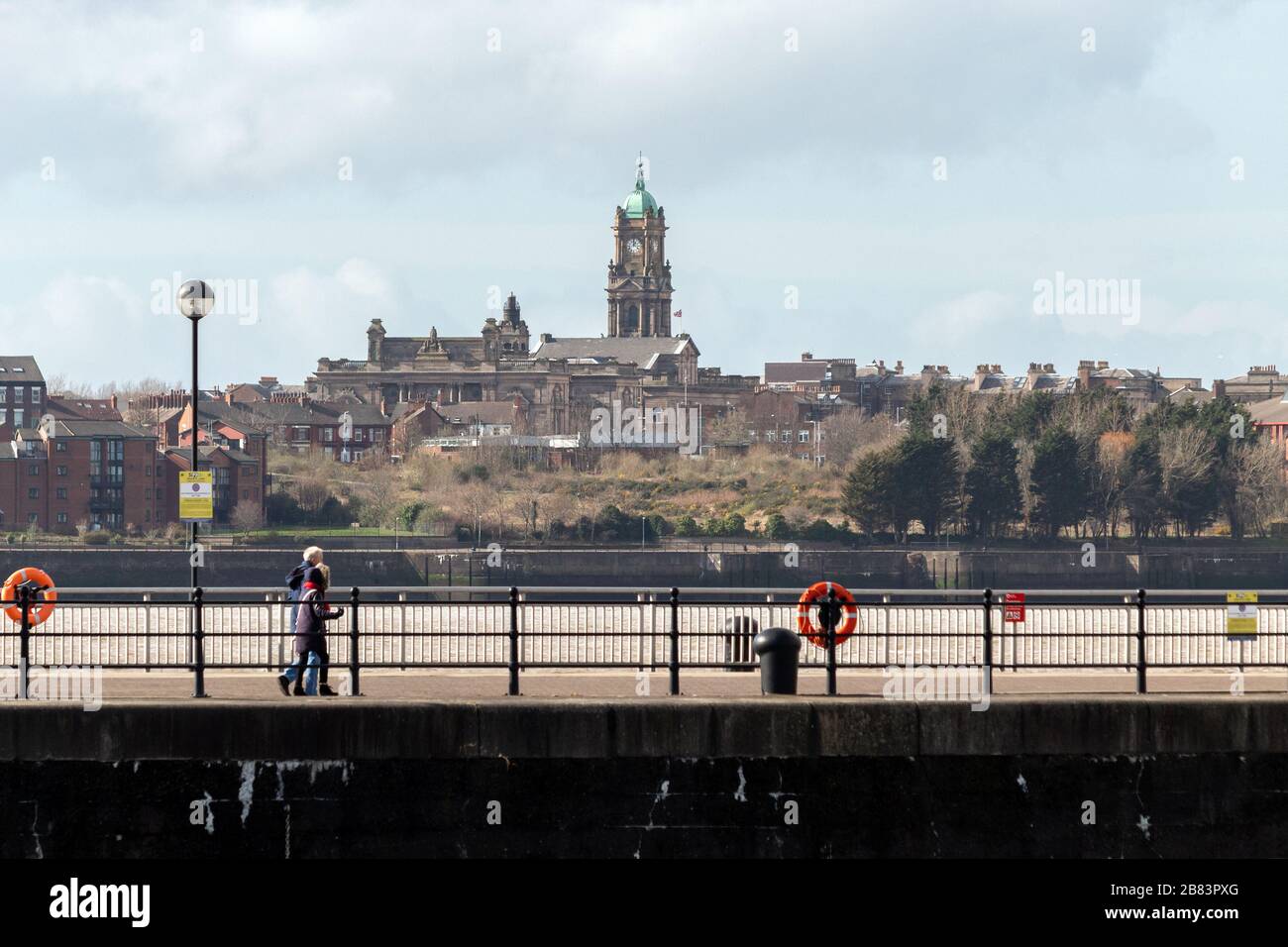 Die Durchgangsstraße Kings Parade am Rande des Queens Dock, Liverpool, mit der Skyline von Birkenhead im Hintergrund. Stockfoto
