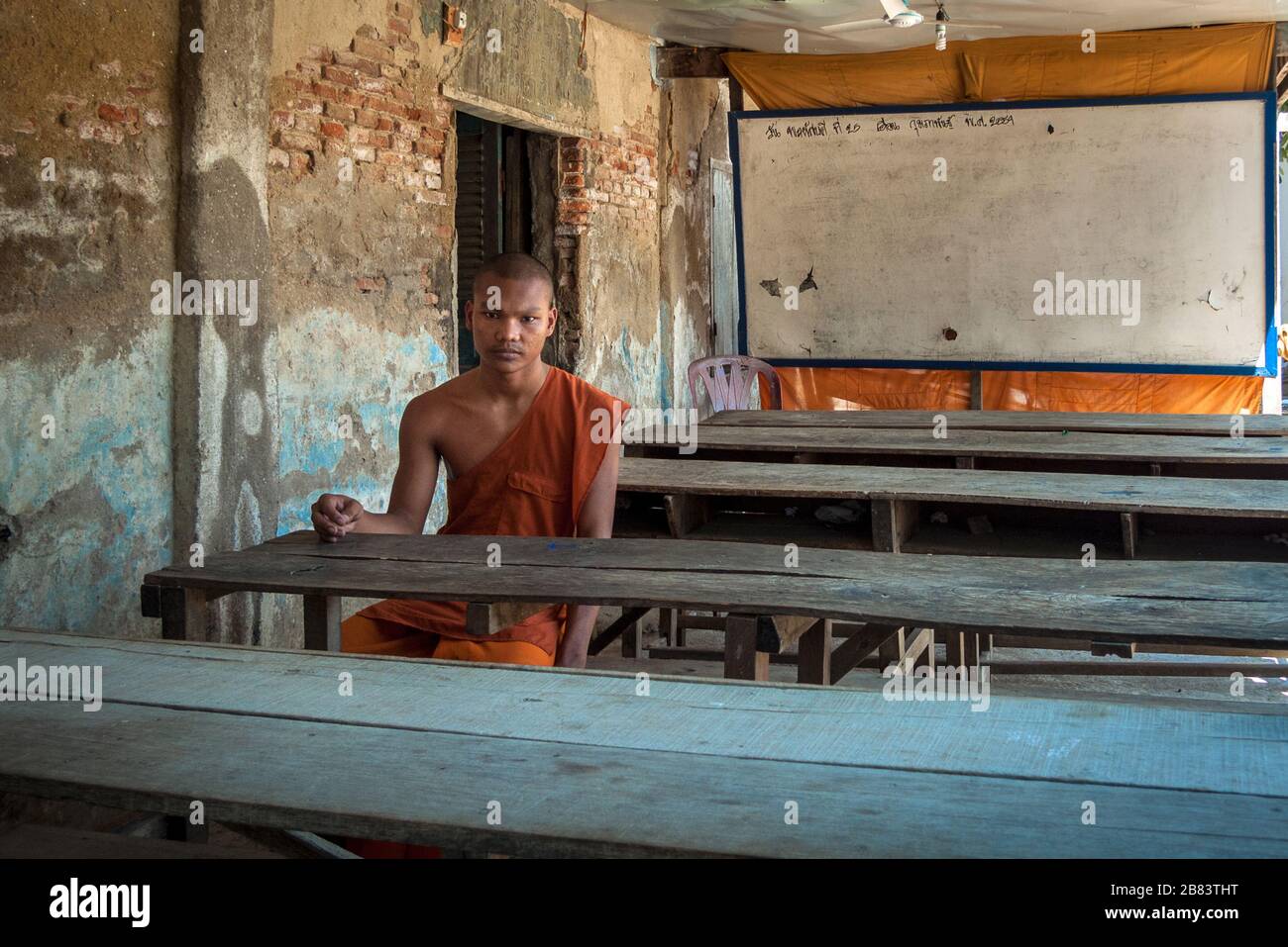 Battambang, Kambodscha, Asien: Junger buddhistischer Mönch, der allein in einem Klassenzimmer einer Außenschule im Tempel Wat Tahm-rai-SAW sitzt Stockfoto