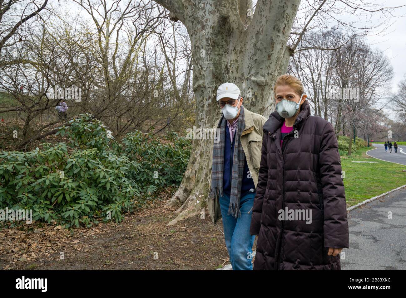New York, USA, 19. März 2020. Ein Paar trägt Gesichtsmasken, während er im Central Park spaziert. Die Menschen in New York verwenden Masken und beobachten soziale Distanc Stockfoto