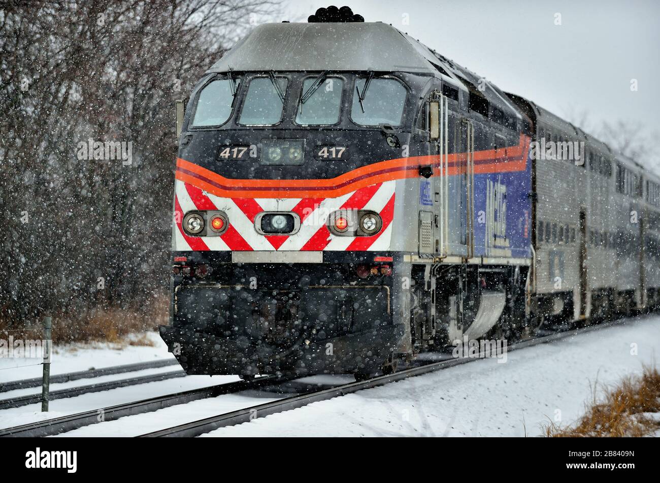 Bartlett, Illinois, USA. Ein Metra-Pendlerzug im Schnee, nachdem er den Pendlerbahnhof Bartlett, Illinois an einem stürmischen Januartag verlassen hatte. Stockfoto