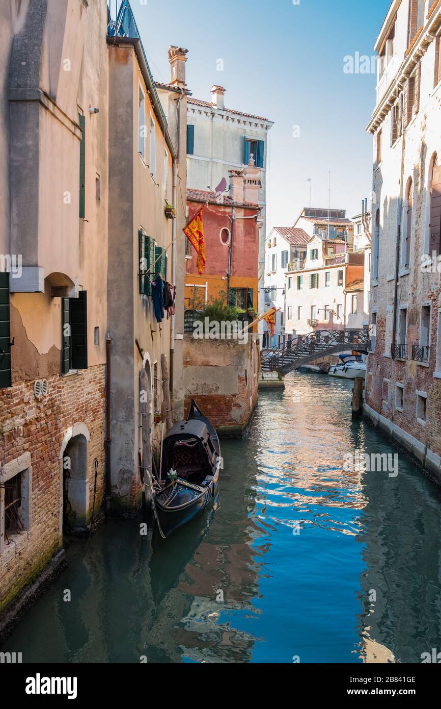 Abseits der Touristengebiete geht es in Venedig, Italien, normal weiter. Wäscherei hängt von den Fenstern, Pflanzen schmücken Balkone, eine Gondel schwebt auf Touristen aus Stockfoto