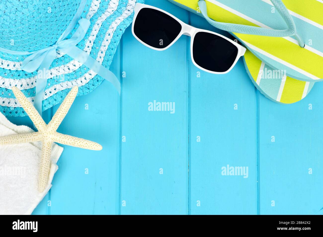 Sommer-Ecke-Grenze von Strandartikeln auf blauem Holzhintergrund Stockfoto