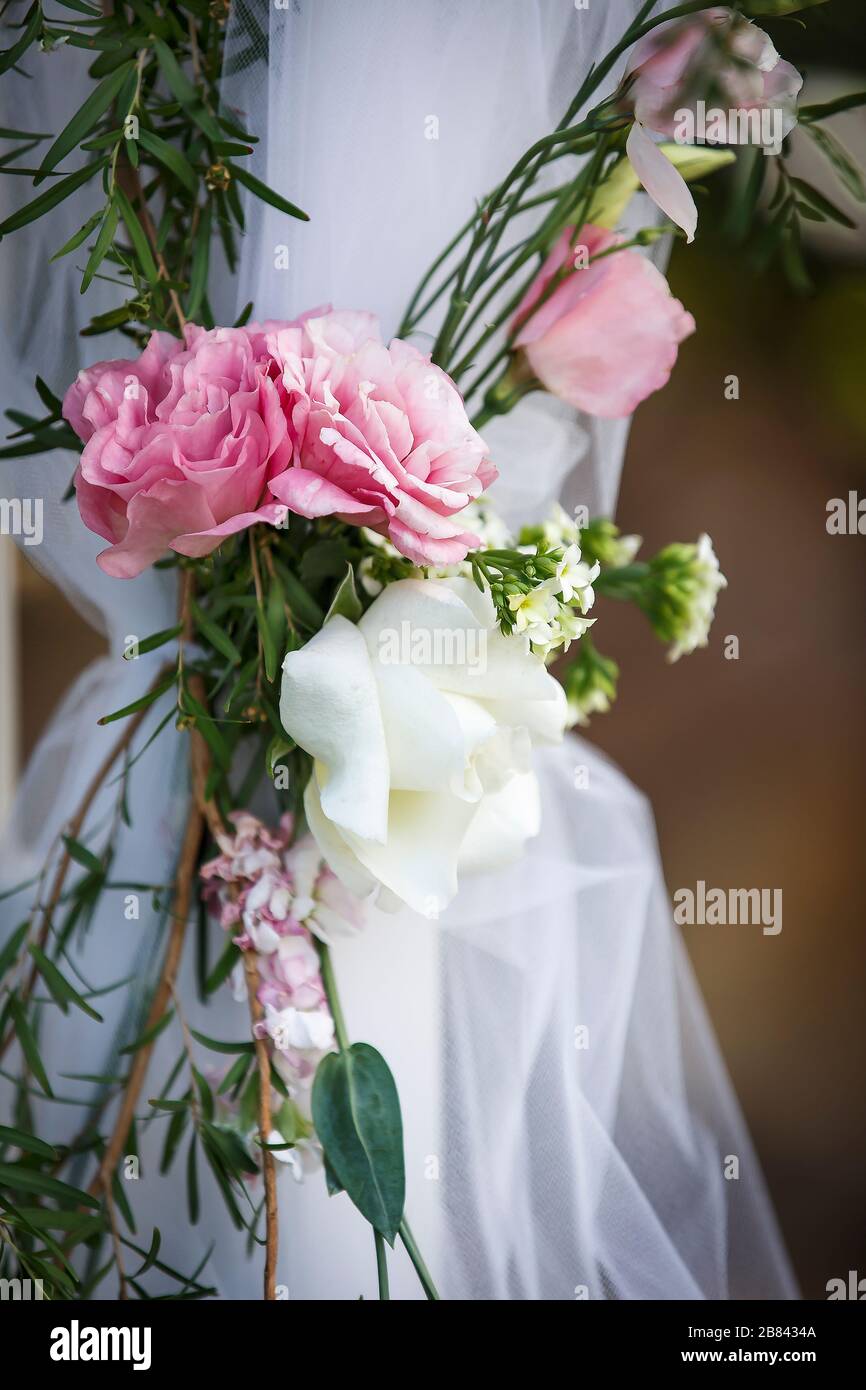 Mit Tüllchen bedeckter Pfosten mit rosa und weißen Rosen, die im Bund für eine Hochzeit im Freien im Frühjahr gebunden sind Stockfoto