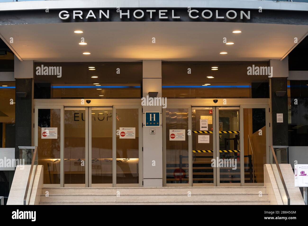 Haupteingang des Gran Hotel Colon Hotels im Stadtzentrum von Madrid. Am 19. März ist das Gran Hotel Colon das erste medizinische Hotel in Spanien geworden, in dem Patienten mit leichten Coronavirus-Symptomen behandelt werden. Die Schilder an den Eingangstüren warnen, dass der Zugang zu unbefugten Personen verboten ist. Das Hotel verfügt über 365 Zimmer, in denen Patienten mit Coronavirus versorgt werden, um Druck von überfüllten Krankenhäusern zu lindern. Stockfoto