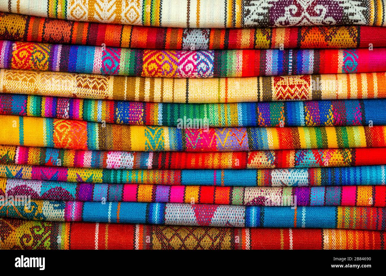 Ein horizontaler Stapel farbenfroher Anden-Stoffe auf dem sonntagsmarkt von Otavalo, Ecuador. Stockfoto