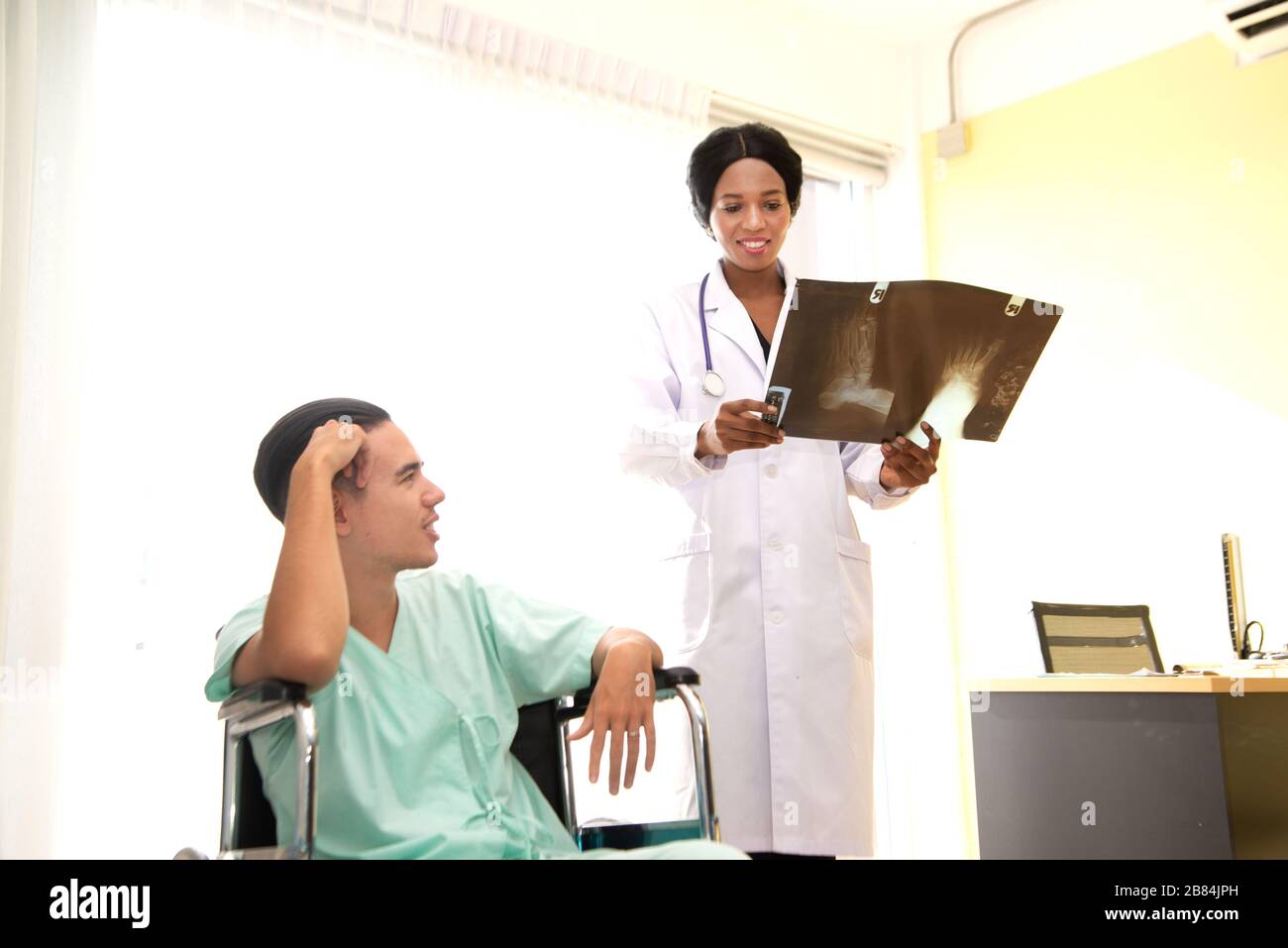 Ein männlicher Patient saß wegen Kopfschmerzen auf dem Rollstuhl. Im Krankenhaus behandelt und von einem Arzt überwacht. Stockfoto