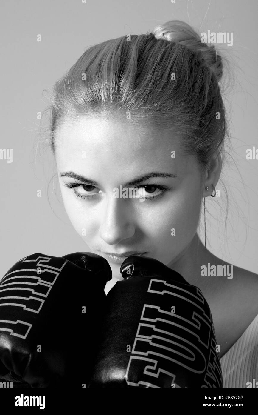 Portrait einer niedlichen, ernsthaften jungen Sportlerin in Boxhandschuhen. Konzept der Bereitschaft, Angst und Kobie zu begegnen. Schwarzweißfoto Stockfoto