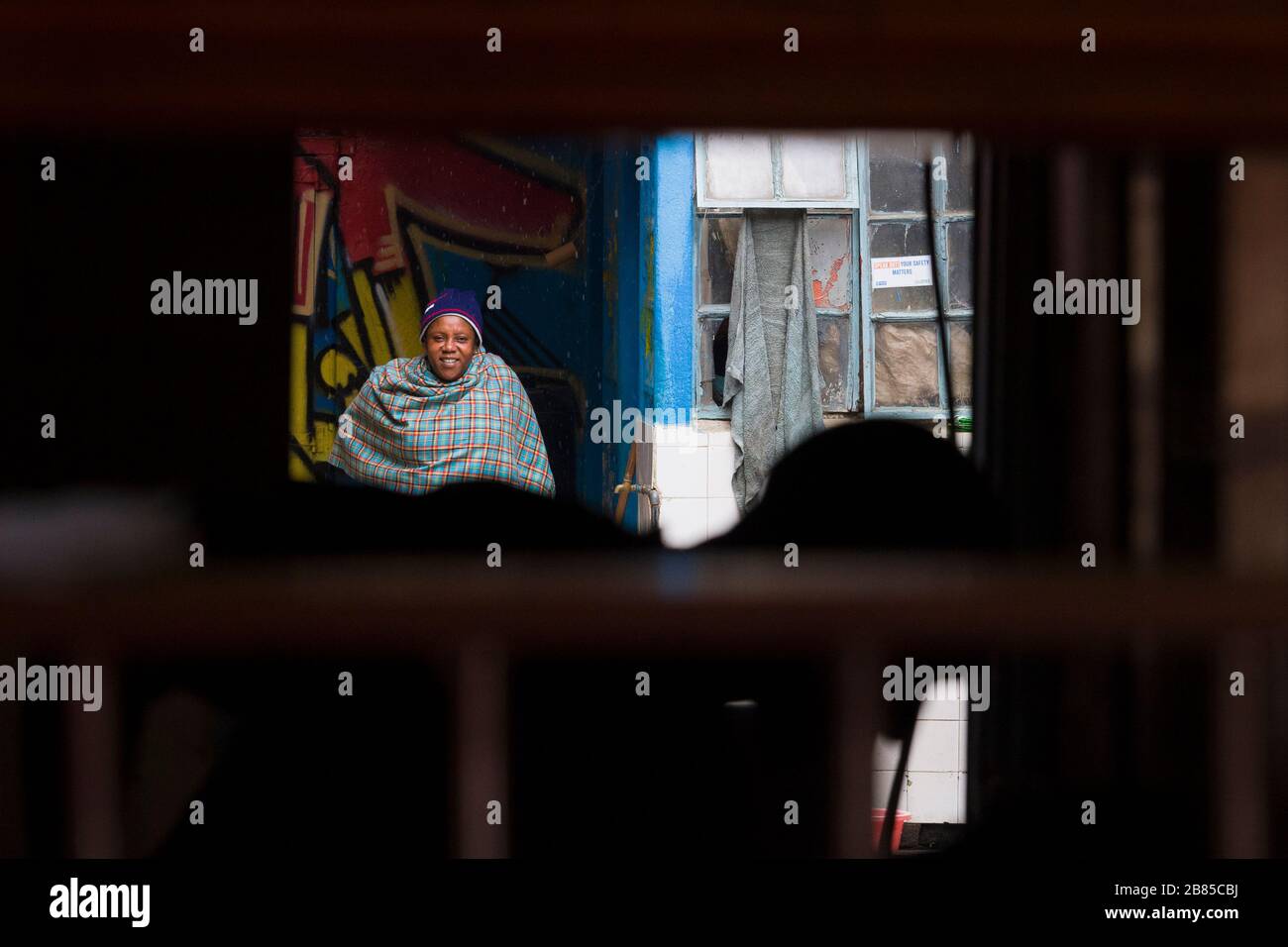 Frau, die eine Schal trägt und vor dem Regen schützt, Mathare, Nairobi, Kenia. Mathare ist eine Sammlung von Slums im Nordosten des zentralen Nairobi, Kenia Wi Stockfoto