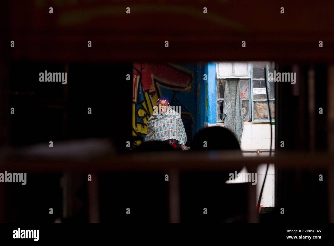 Frau, die eine Schal trägt und vor dem Regen schützt, Mathare, Nairobi, Kenia. Mathare ist eine Sammlung von Slums im Nordosten des zentralen Nairobi, Kenia Wi Stockfoto