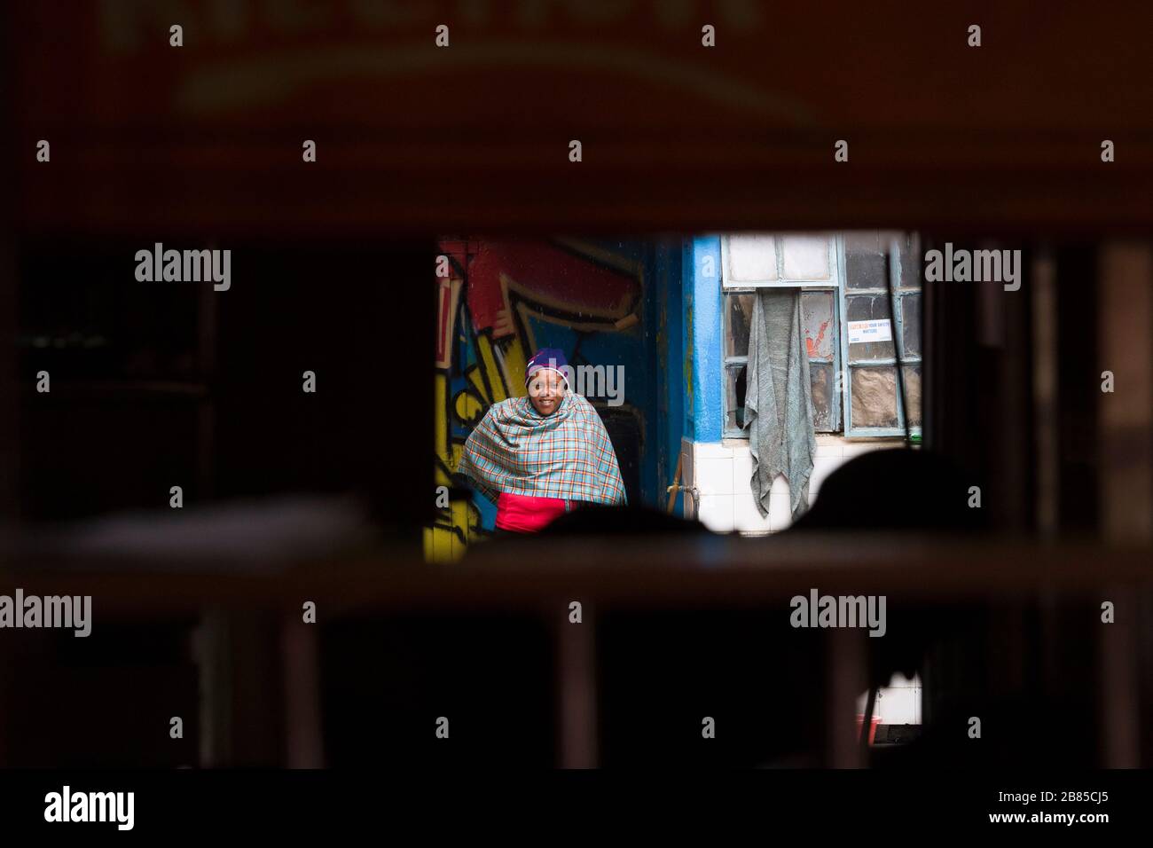 Frau, die eine Schal trägt und vor dem Regen schützt, Mathare, Nairobi, Kenia. Mathare ist eine Sammlung von Slums im Nordosten des zentralen Nairobi, Kenia Wi Stockfoto