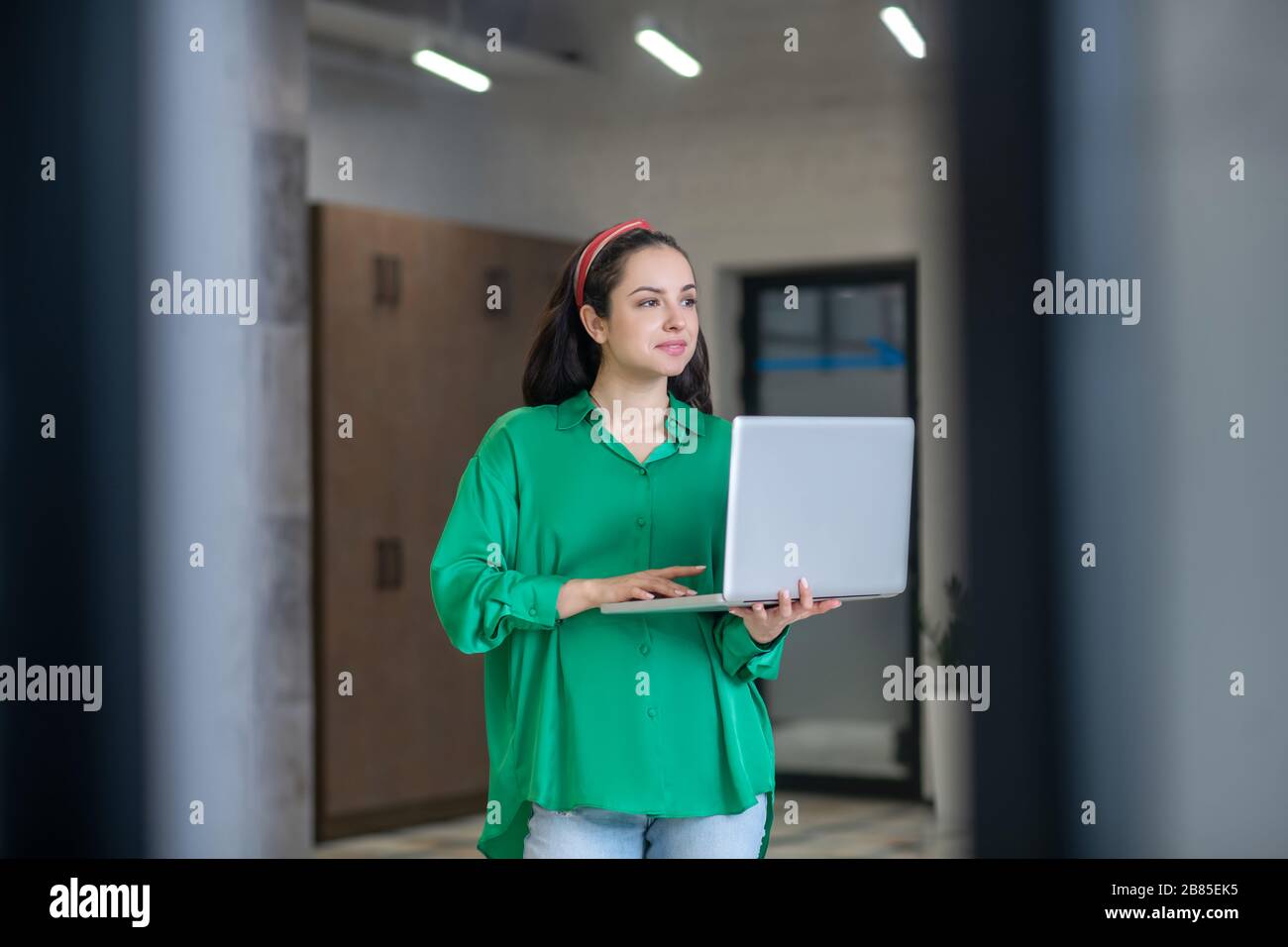 Frau im Flur mit einem Laptop in Gedanken stehen. Stockfoto