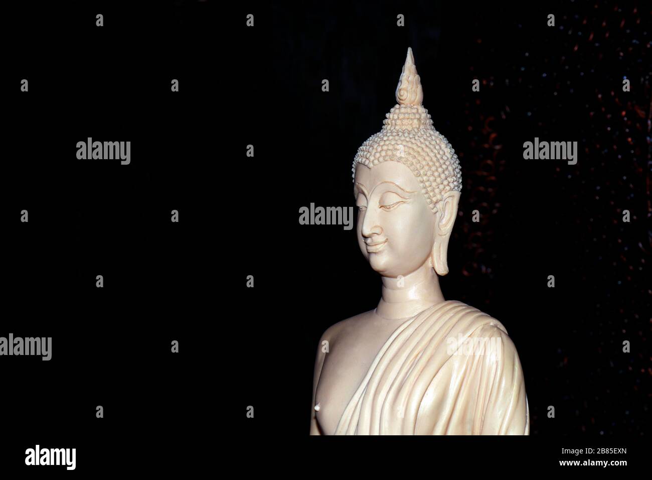 Die weiße Buddha-Statue auf schwarzem Grund besteht aus elfenbeinfarbenem, weiß geschnitztem Elfenbein Stockfoto