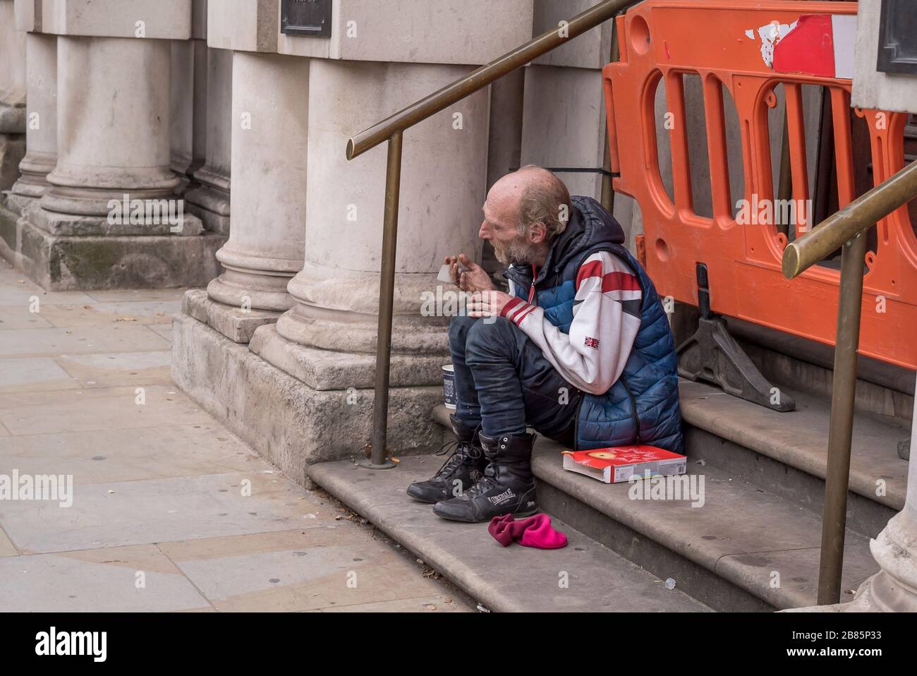Trauriger Obdachloser, der in der Tür auf der Straße im Zentrum von London in Großbritannien sitzt. Obdachlosigkeit in Großbritannien schlafen Menschen ohne Zuhause in der Stadt grob betteln. Stockfoto