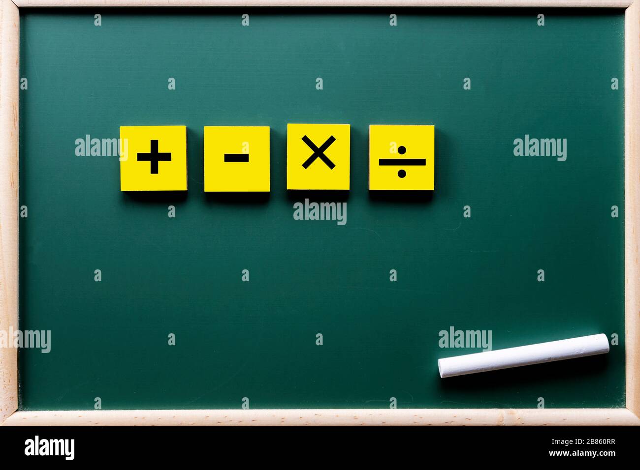 Mathematische Symbole addieren, subtrahieren, multiplizieren, dividieren, auf dem Blackboardmodell platzieren. Die weiße Kreide ist zusammengebaut. Stockfoto