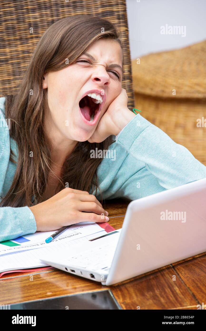 Schöne müde Mädchen Studentin macht ihre Hausaufgaben beim Gähnen Stockfoto