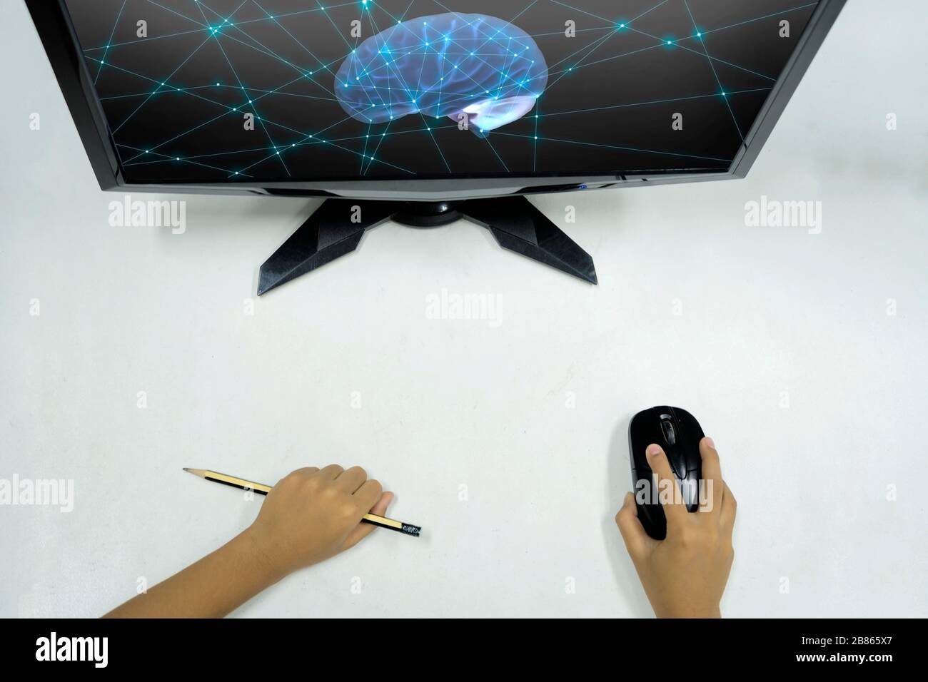 Innovatives Lernkonzept. Die Hand des Kindes, mit der eine Maus zum Bedienen des Computers und anderer Geräte gehalten wurde, war ein Bleistift. Der Bildschirm ist leer. Stockfoto
