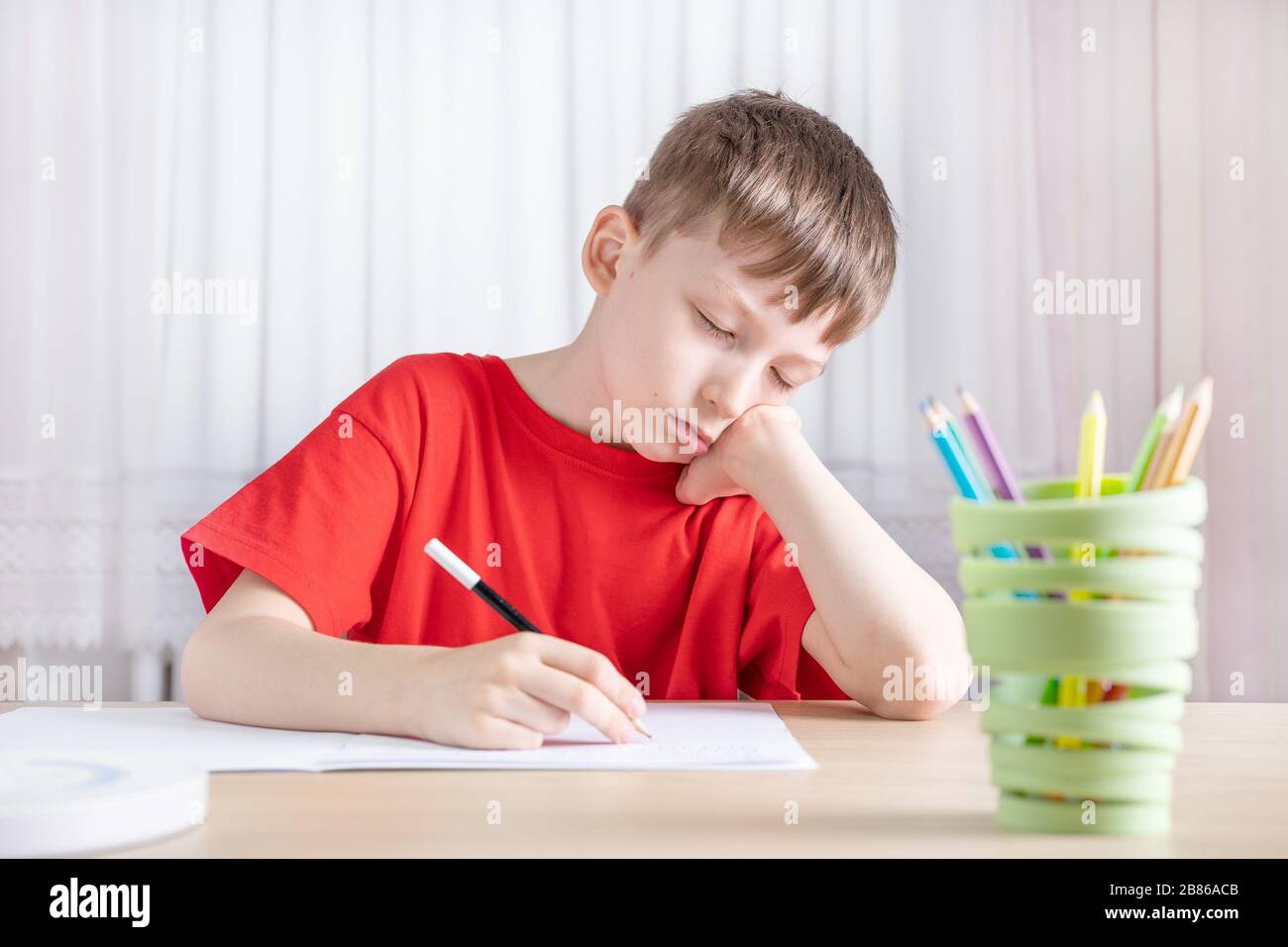 Müder Junge, der Hausaufgaben macht, Bild des Schulkonzepts Stockfoto