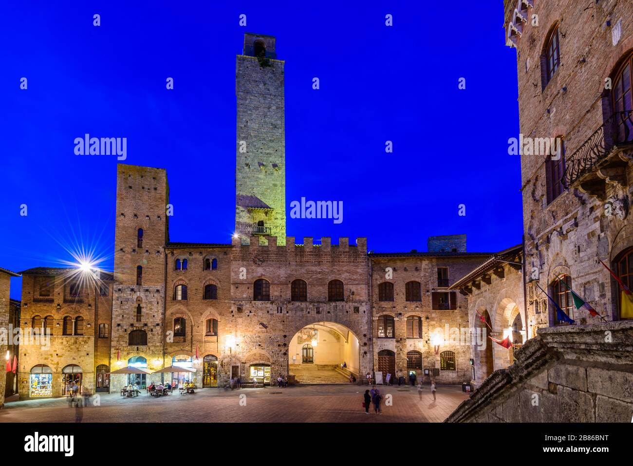 San Gimignano, Toskana: Palazzo Vecchio del Podestà mit Torre Rognosa hinter dem Gebäude und dem Palazzo Comunale rechts in der Piazza del Duomo bei Dämmerung. Stockfoto