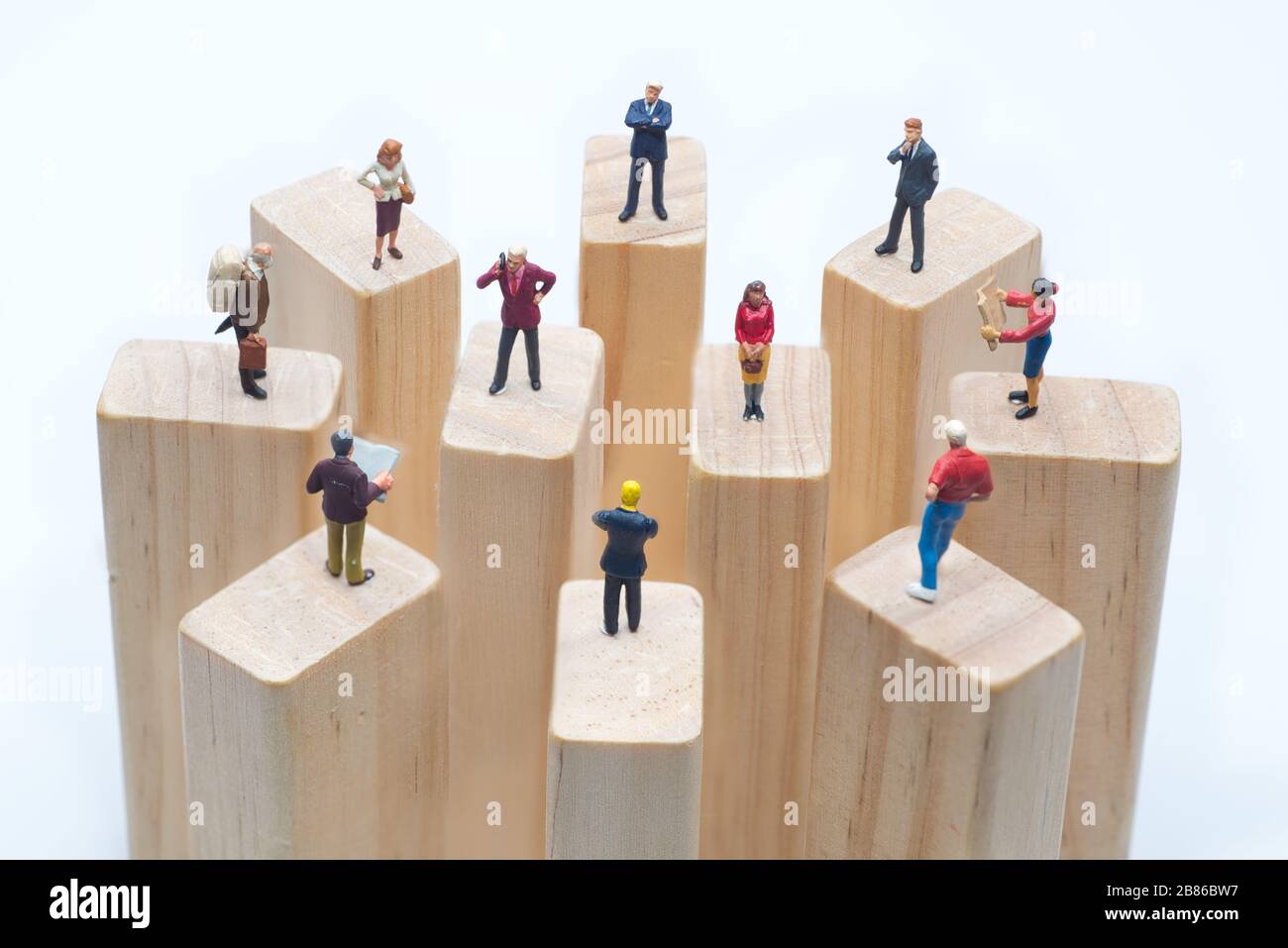 Miniaturspielzeuge, die auf Holzklotz stehen - soziale Distanzierung, anti-soziales Konzept oder Teamarbeit. Stockfoto