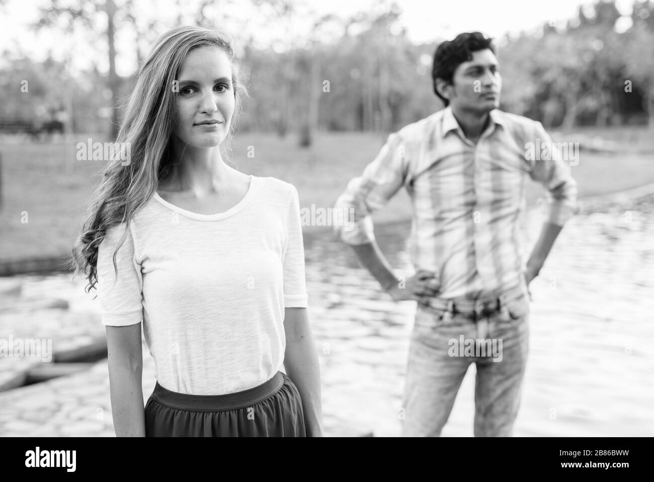 Schöne Frau mit indianischem Mann, die denkt und auf einem Steinpfad mitten im See im Park steht Stockfoto