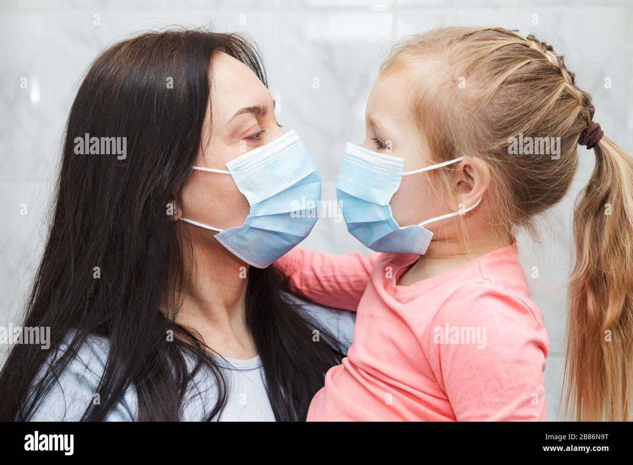 Frau und Mädchen tragen medizinische Masken. Stockfoto