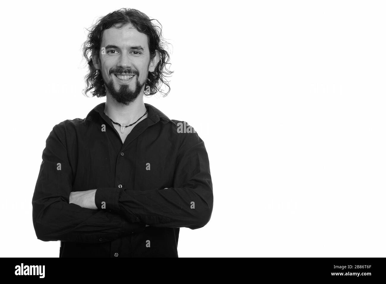 Porträt eines glücklichen, gutaussehenden bärtigen Geschäftsmannes, der mit gekreuzten Armen lächelte Stockfoto