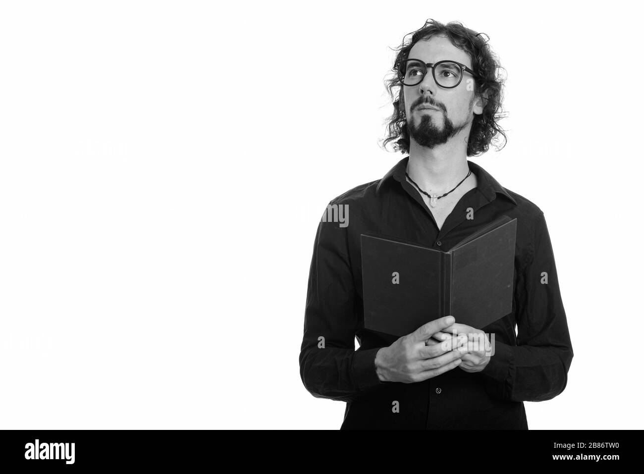 Portrait von hübschen bärtigen Geschäftsleuten mit Brillen, die während des Buchs denken Stockfoto