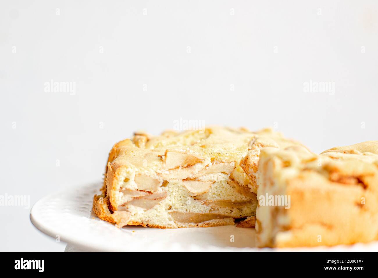 Hausgemachte Biobausen-Apfelkuchen-Dessert Charlotte. Pflaster Apple Pie auf weißem Teller und weißem Hintergrund Stockfoto