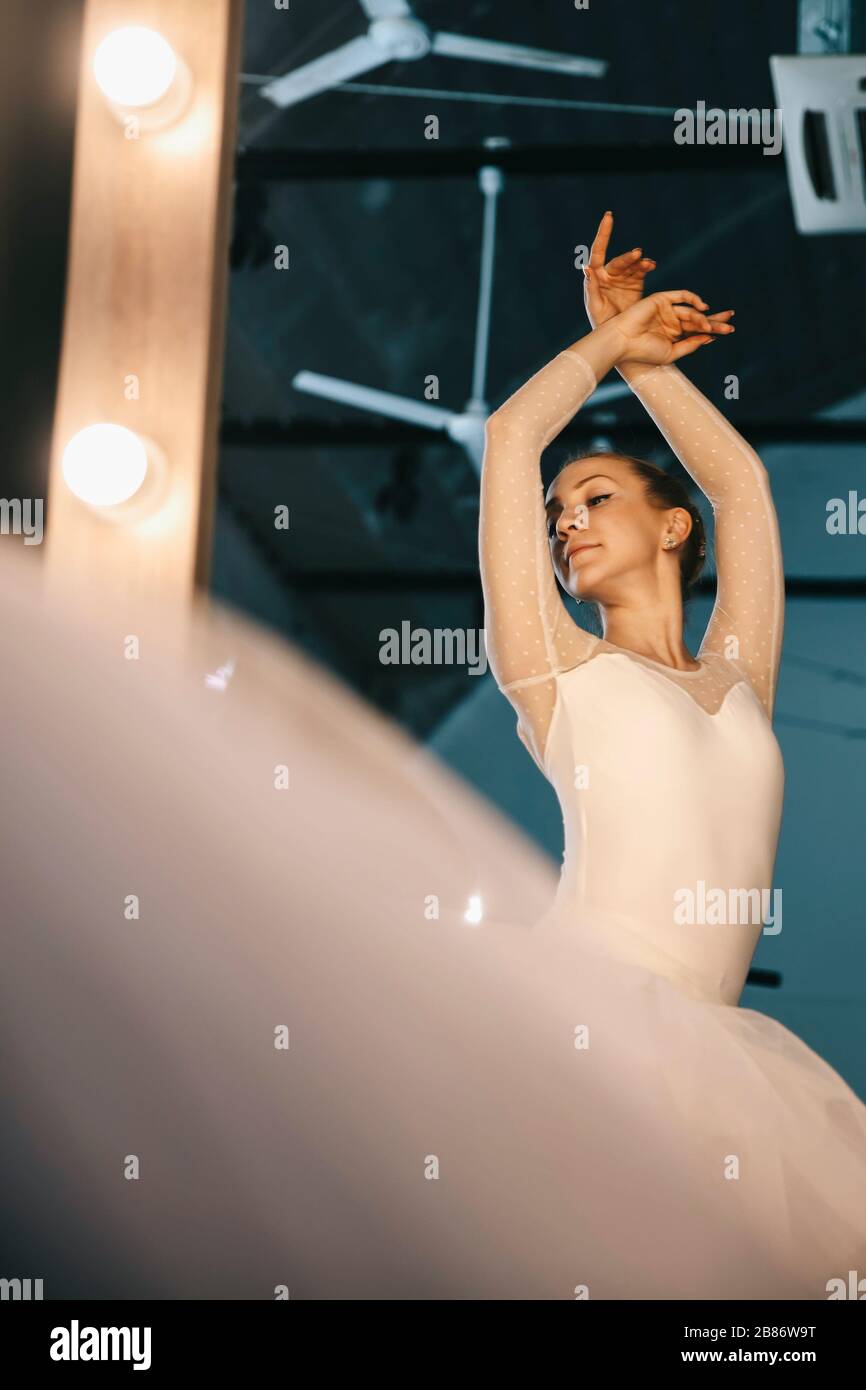 Junge Ballerina in weißem Kleid mit perfektem Körper tanzt im Studio Stockfoto