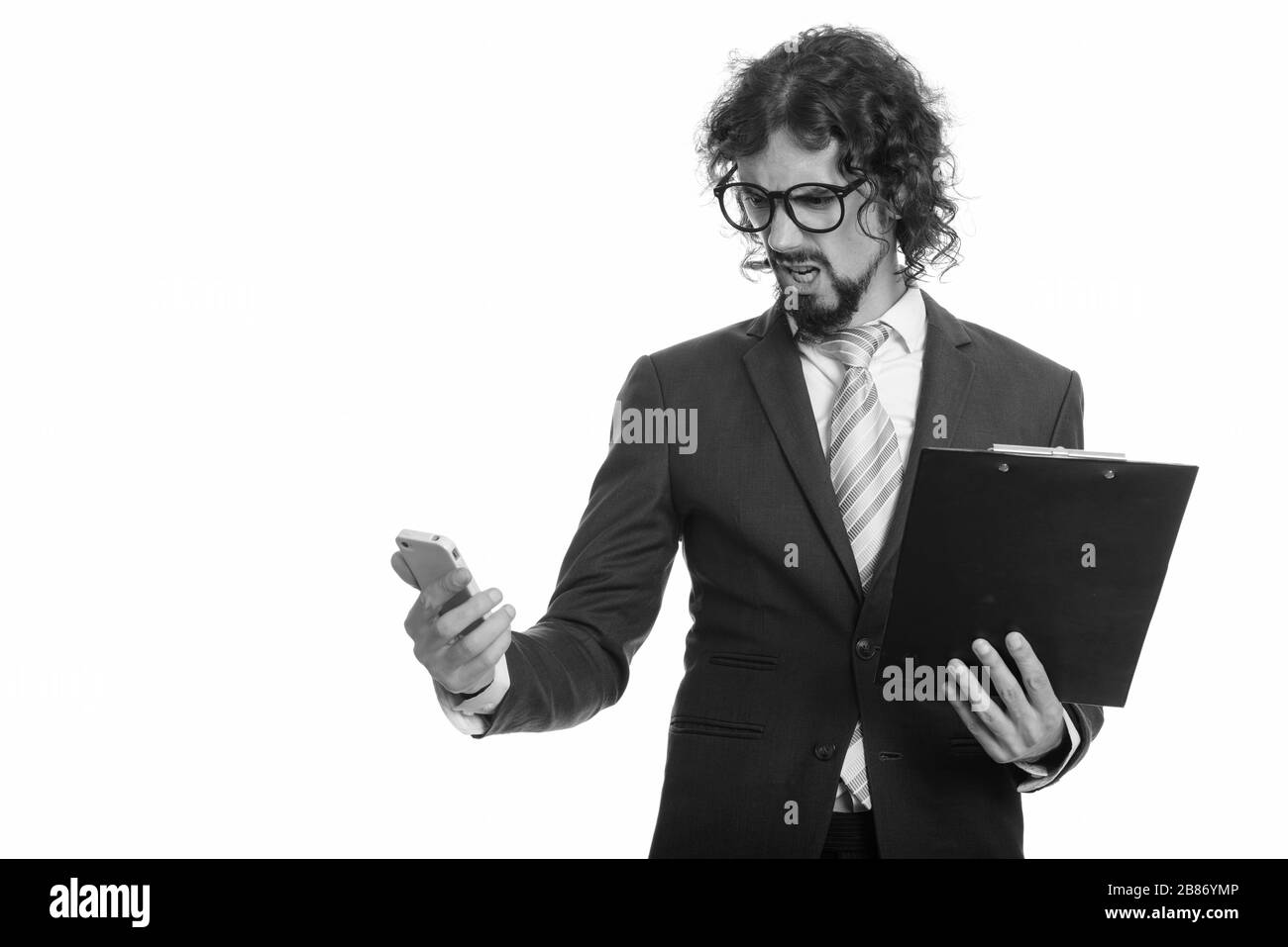 Stattlichen kaukasischen Geschäftsmann holding Zwischenablage und Mobiltelefon, während sie wütend Stockfoto