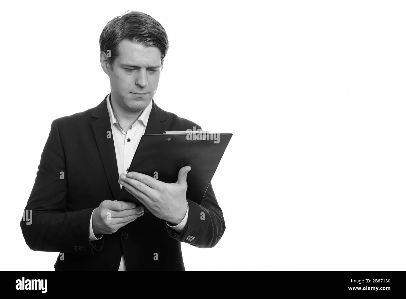 Portrait junger, gutaussehender Unternehmer, der in der Zwischenablage liest Stockfoto