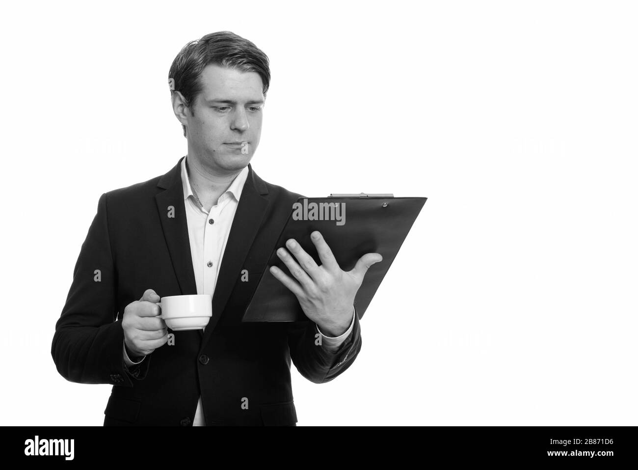 Stattlichen kaukasischen Geschäftsmann Zwischenablage lesen, während Sie Kaffee Tasse Stockfoto