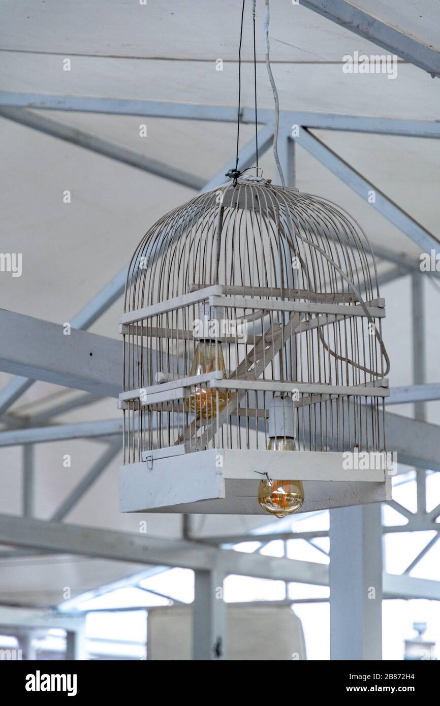 Lampenschirm aus weiß bemaltem Holz Vogelkäfig. Nahaufnahme des Vogelkäfigs  in Deckenlampe mit goldener Glaslampe im Inneren verwandelt Stockfotografie  - Alamy